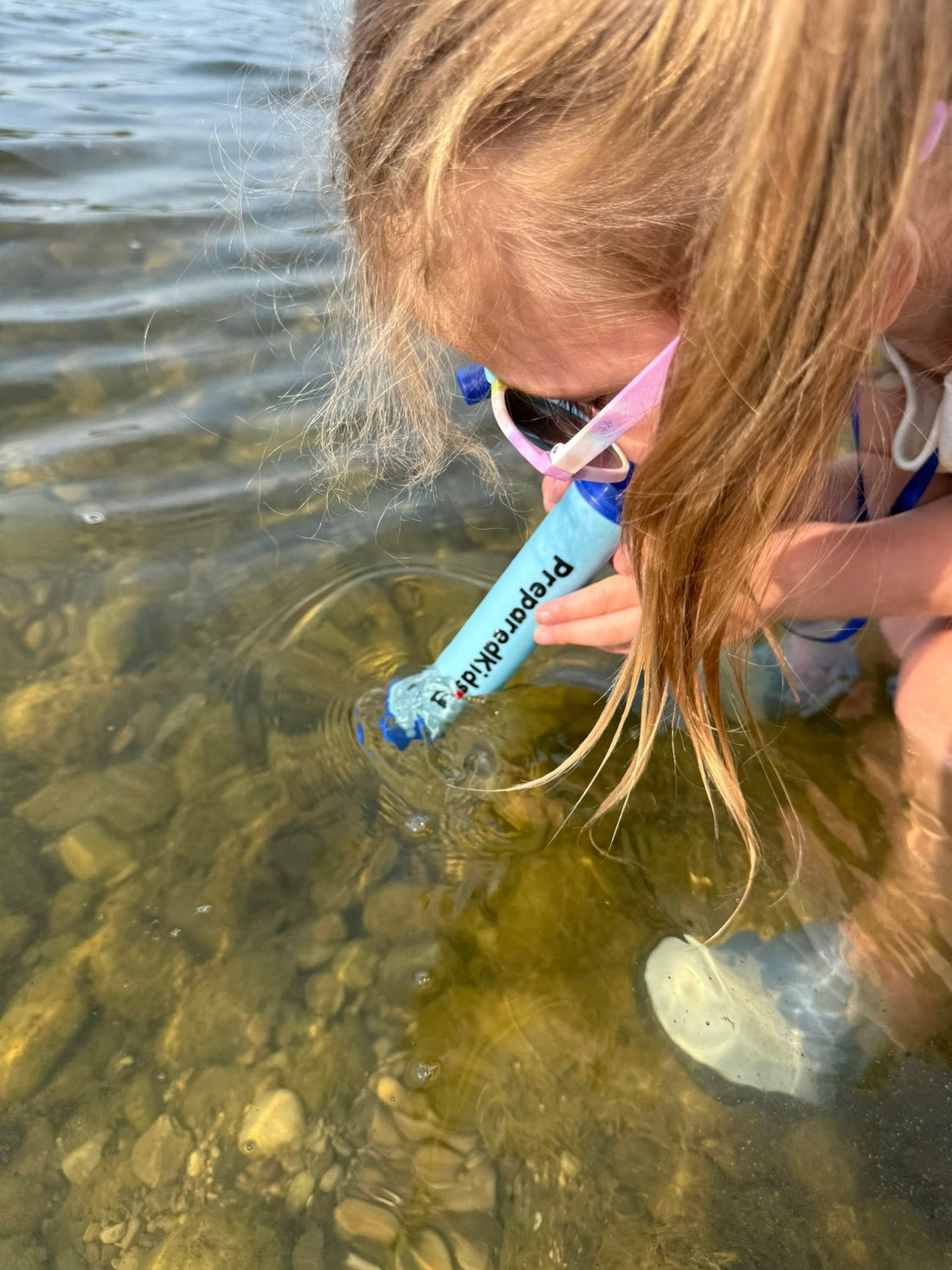 Prepared Kids emergency survival backpack kit water filtration straw life straw girl drinking water from a river using a water filtration straw
