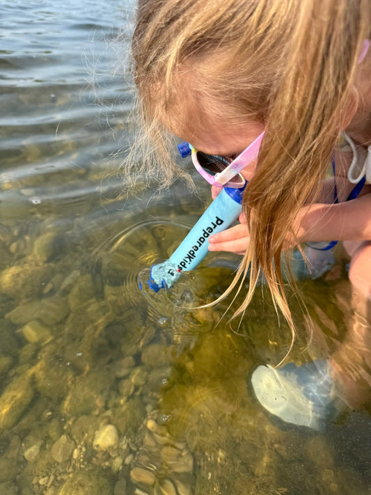 Prepared Kids emergency survival backpack kit water filtration straw life straw girl drinking water from a river using a water filtration straw  